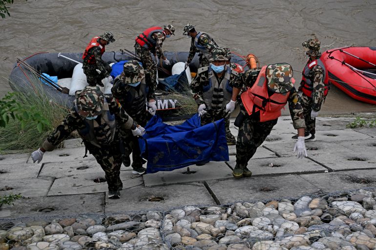 Nepal's army personnel carry the bodies of deceased flood victims during a search operation along the Narayani river at Bharatpur in Nepal's Chitwan district on August 31, 2026. Nepal was burying on August 31 some of the hundreds of bodies retrieved after a deadly, tsunami-like flood crashed through the Himalayan region, sweeping away villages and leaving thousands still missing. (Photo by PRAKASH MATHEMA / AFP)