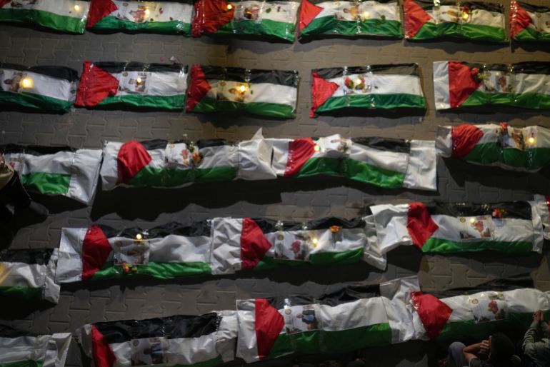 Mourners light candles by the bodies of Palestinians recovered from the rubble of homes demolished during the Israel-Hamas war in Gaza City