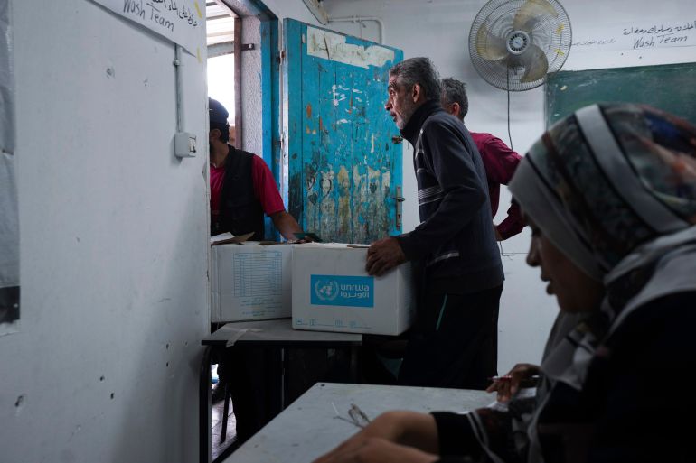 Palestinians receive aid distributed by UNRWA, in Nusairat refugee camp, Gaza