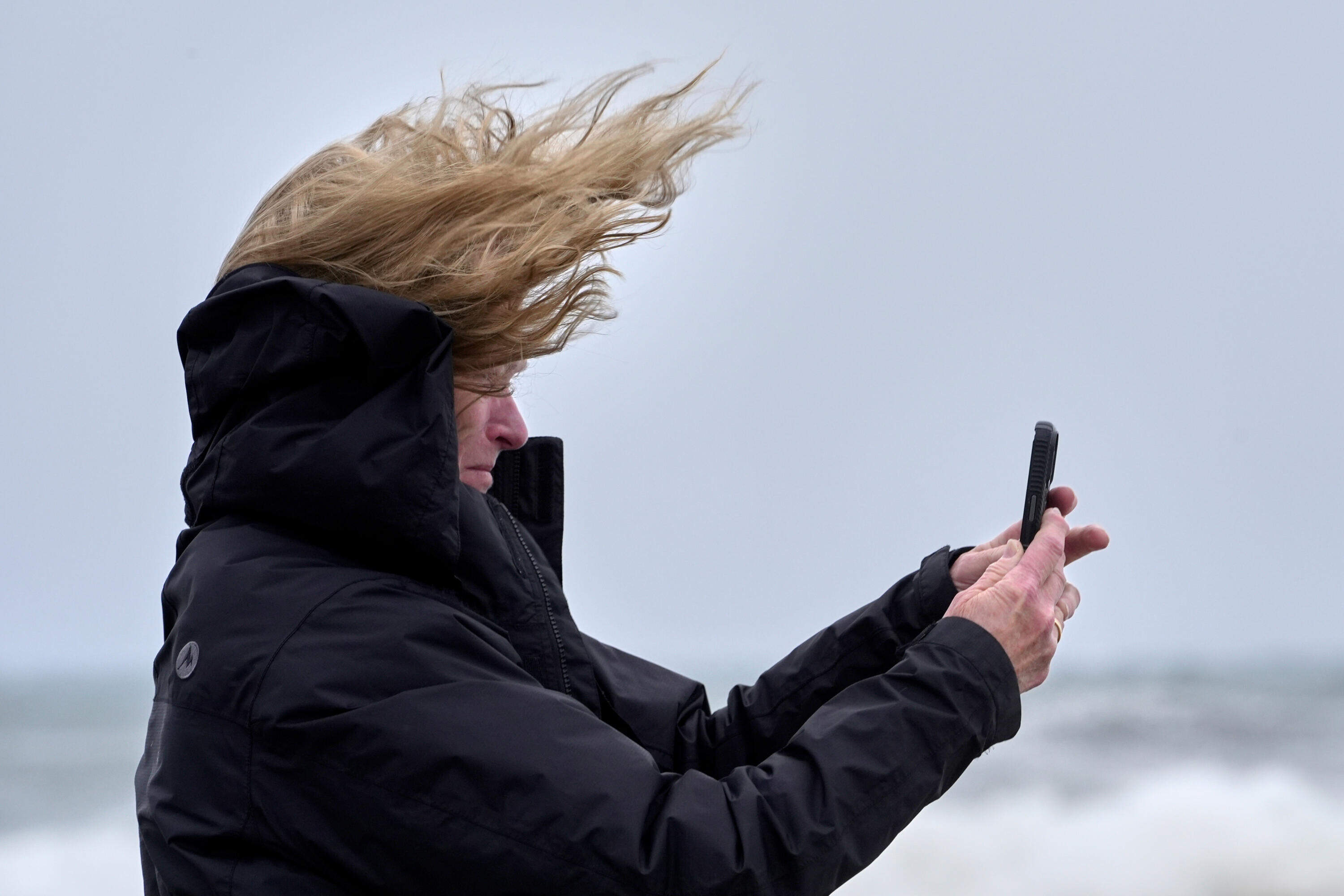 Denise Taylor of Manchester, N.H., is buffeted by the wind as she films the raging sea during a nor'easter in Hampton, N.H. (Robert F. Bukaty/AP)
