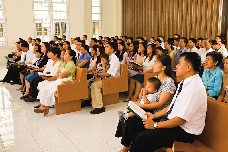 A congregation sits together and sings a hymn during a sacrament meeting.