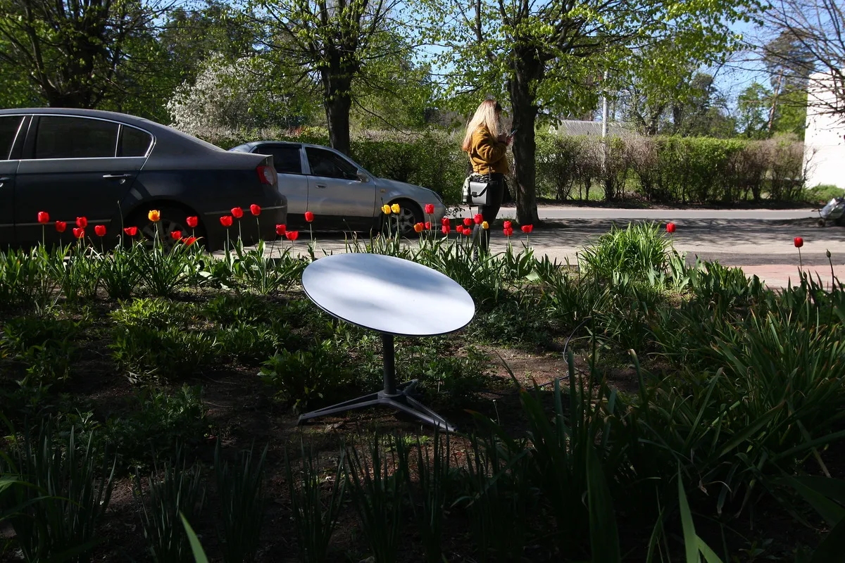 A person looks at a smartphone near a SpaceX Starlink internet terminal installed on a flower bed on May 5, 2022 in Vorzel, Ukraine.