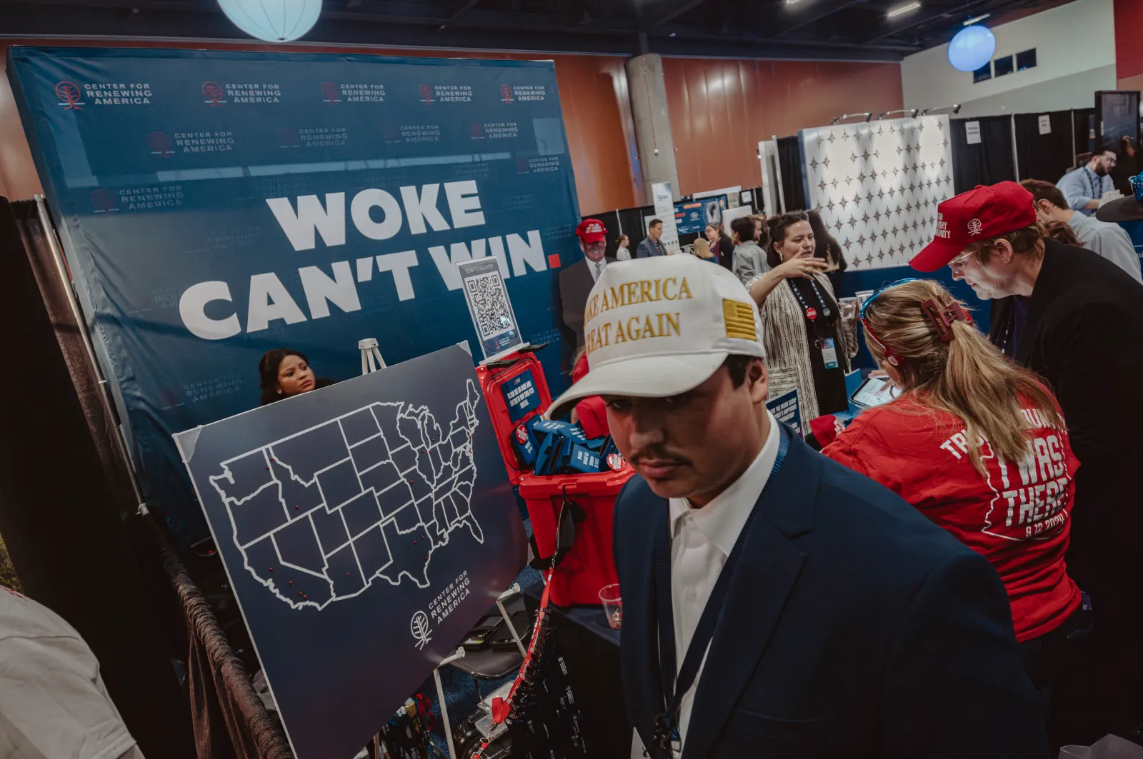 Guests are pictured near a banner reading "woke can't win" as they await the start of Turning Point's annual AmericaFest conference, in remembrance of late right-wing political activist Charlie Kirk, in Phoenix, Arizona, on December 18, 2025. (Photo by Olivier Touron/AFP via Getty Images)