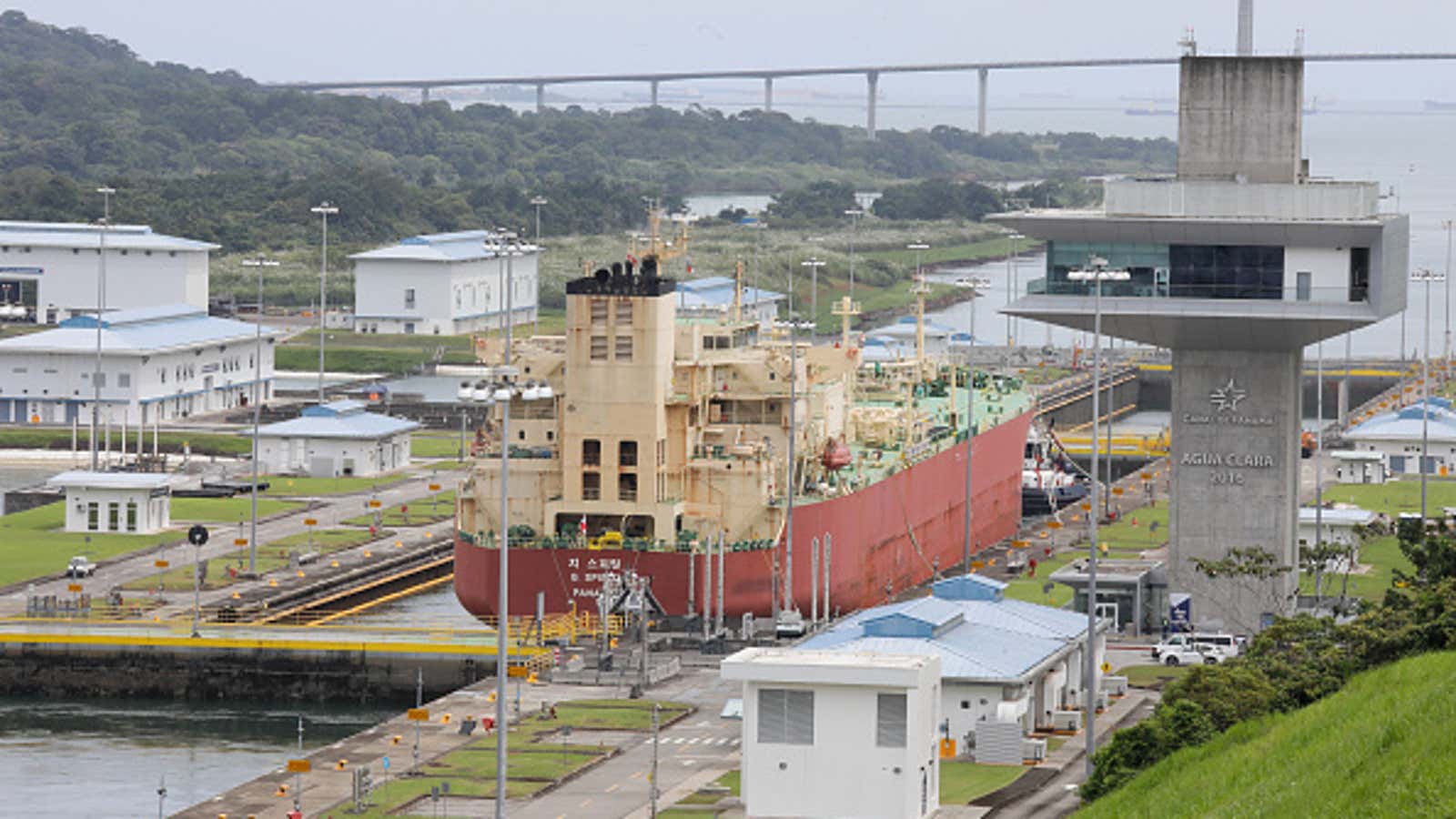 Cargo ship passing through Agua Clara locks at the Panama Canal, with a bridge visible in the background