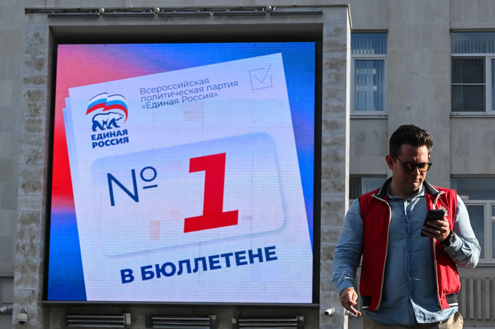 A man walks past a digital screen on the building of the United Russia party's headquarters in Moscow on September 15, 2026, calling people to vote in the election for Russia's lower house of parliament.