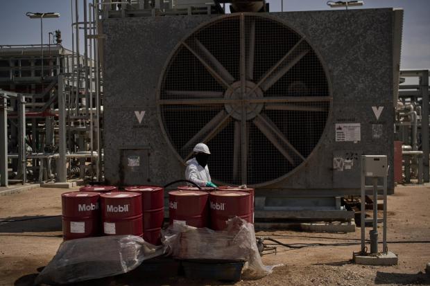 A worker collects engine oil as he works at a degassing station in Zubair oil field.