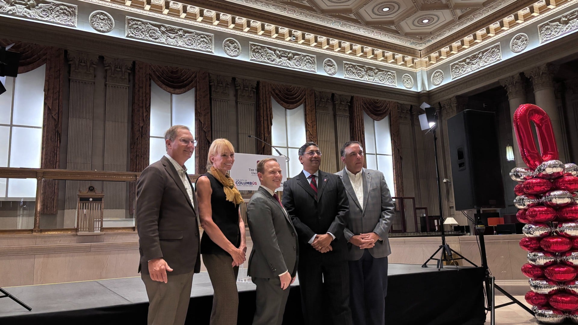 five people pose for photos in an ornate room