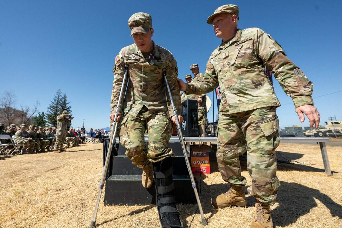 Chief warrant officer 5 James Carr, right, helps Purple Heart recipient Spc. Christopher Nieto to his seat during a soldiers’ homecoming and medal ceremony at B.T. Collins U.S. Army Reserve Center in Sacramento on Saturday.