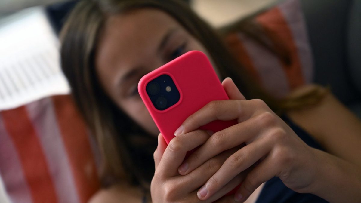 A teenager looks at her smartphone in Brussels on July 7, 2026. The European Commission estimated, on July 6, 2026, that the French bill banning social media access for children under 15 was not fully compatible with European Union law, while reaffirming its support for the initiative. Like France, Spain and Denmark are also working on the introduction of a digital age of majority to follow Australia's example, who became in December 2025 the first country to implement such a law. (Photo by Nicolas TUCAT / AFP via Getty Images)