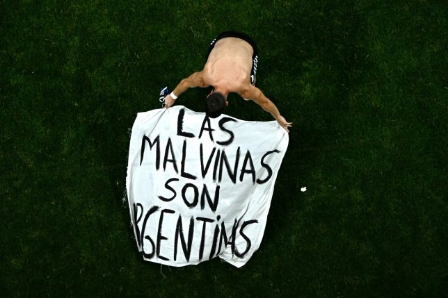 TOPSHOT - Argentina's midfielder #11 Giovani Lo Celso adjusts a banner reading "The Malvinas (Falkland Islands) belong to Argentina," after winning the 2026 World Cup football tournament semi-final match between England and Argentina at the Atlanta Stadium in Atlanta on July 15, 2026. (Photo by Jewel SAMAD / AFP via Getty Images)