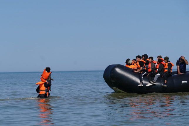 People thought to be migrants wade in the water as they attempt to board a small boat off the coast of Hardelot, France, during an attempt to cross the English Channel. Picture date: Wednesday July 29, 2026. PA Photo. Photo credit should read: Gareth Fuller/PA Wire