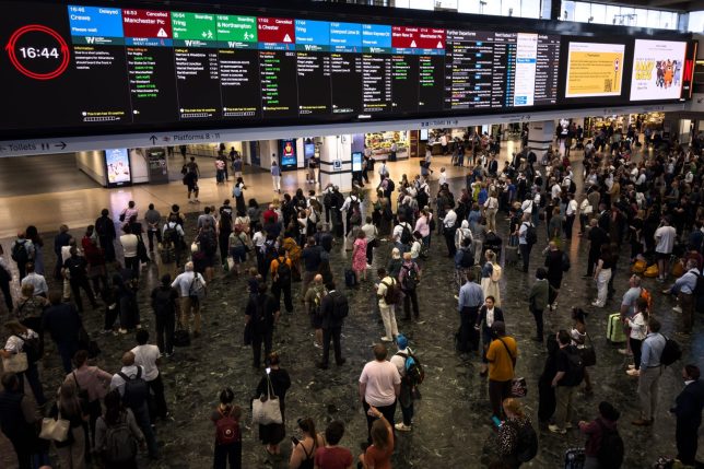 LONDON, ENGLAND - AUGUST 06: Passengers look towards the departure boards as trains are cancelled and delayed from leaving Euston after a major disruption to rail service in the Midlands and northwest England on August 06, 2026 in London, England. National Rail has said a power failure at a communications centre has affected five rail companies: Avanti West Coast, East Midlands, Northern, TransPennine Express and Transport for Wales. (Photo by Leon Neal/Getty Images)