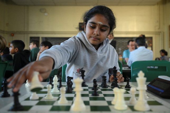 Bodhana Sivanandan, age 11, moves a piece as she plays a posed chess game with a Reuters journalist while filming part of an interview segment at Harrow Chess Club in Harrow, London, Britain, April 23, 2026. REUTERS/Jaimi Joy