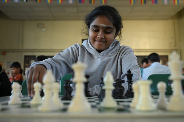 Bodhana Sivanandan, age 11, moves a piece as she plays a posed chess game with a Reuters journalist while filming part of an interview segment at Harrow Chess Club in Harrow, London, Britain, April 23, 2026. REUTERS/Jaimi Joy