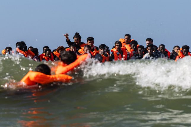 TOPSHOT - Migrants try to board a smuggler's boat off the beach of Equihen-Plage, northern France, on September 23, 2026. The body of a man was found on the beach at Neufchatel-Hardelot (Pas-de-Calais) on September 23, 2026, morning, shortly after an attempted migrants departure for England, AFP journalists observed. His death was pronounced shortly after 9:00 a.m. by the fire brigade, AFP noted. (Photo by Sameer Al-DOUMY / AFP via Getty Images)