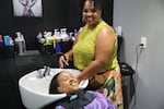 Yanna Hortona washes the hair of Courtney Trent at L&M Hair Lounge on Northeast Broadway in Portland, Ore., on Aug. 26, 2026. Hortona has built wiggle room into her calendar and is warning clients to expect delays. Trent says she’s not worried about her own short commute but as an administrative assistant at Parkrose High School, she is concerned about student attendance.