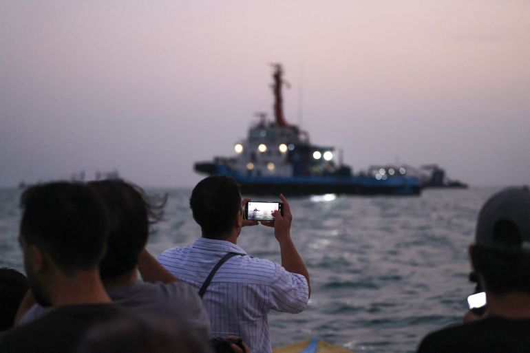 People on a boat take pictures of vessels as they transit the Strait of Hormuz off the coast of the port city of Bandar Abbas in southern Iran on September 5, 2026.