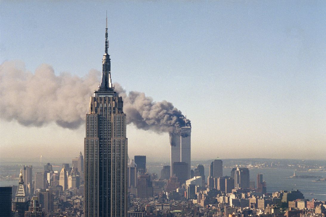 The twin towers of the World Trade Center burn behind the Empire State Building in New York, Sept. 11, 2001.
