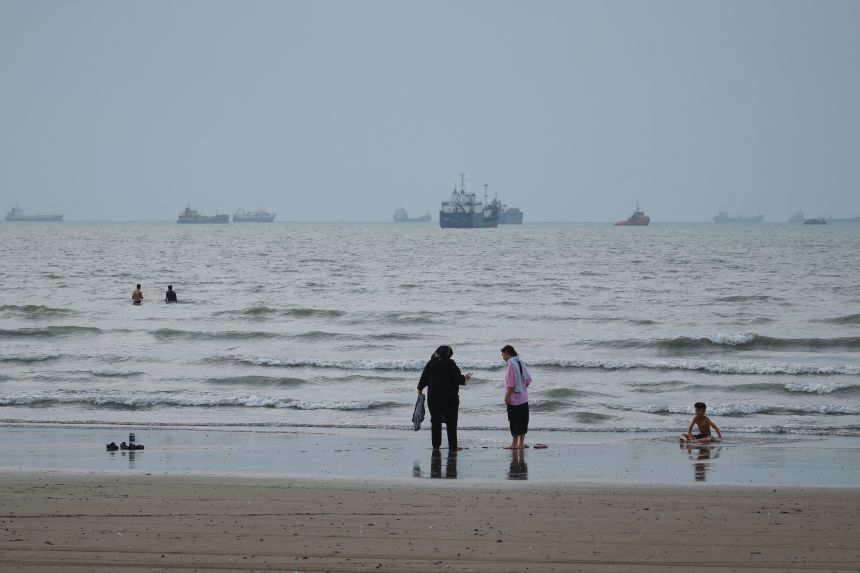 People spend time at a beach as commercial vessels are anchored in the Strait of Hormuz off Bandar Abbas, Iran, on Wednesday, Sept. 2.
