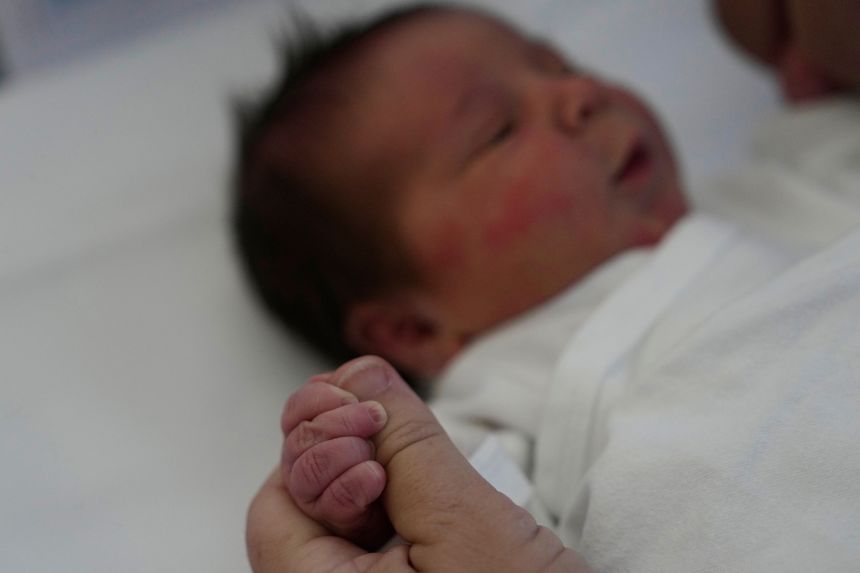 Cristina Rapti-Tzelepi, 54, holds the hand of her 3-day-old daughter, Georgia.