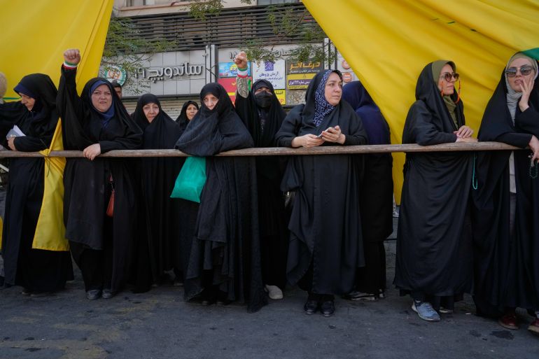 Women watch the state-organized "Janfada," or "Sacrifice for Iran," military-style parade as one raises her fist in Tehran, Iran, Friday, Sept. 18, 2026. (AP Photo/Vahid Salemi)