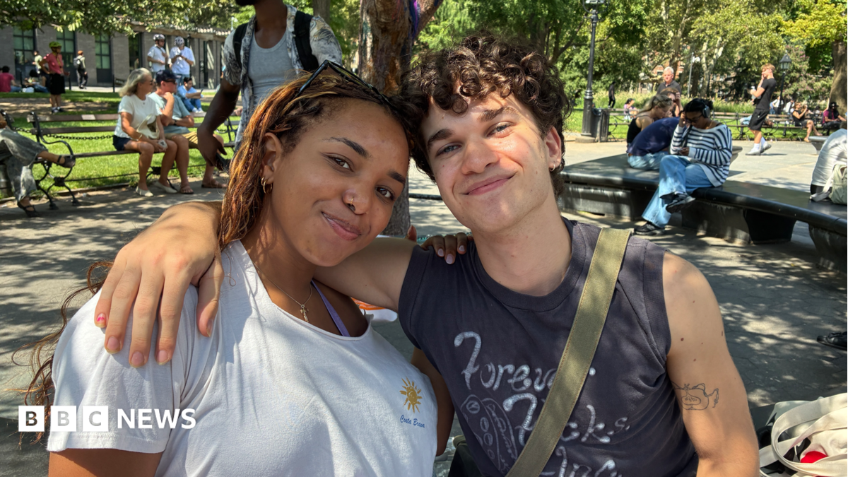 A woman and a man sit on a bench in a park
