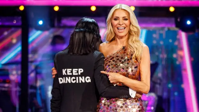 Claudia Winkleman and Tess Daly pictured during Strictly 2025 final, with the words "Keep dancing" emblazoned on Winkleman's jacket