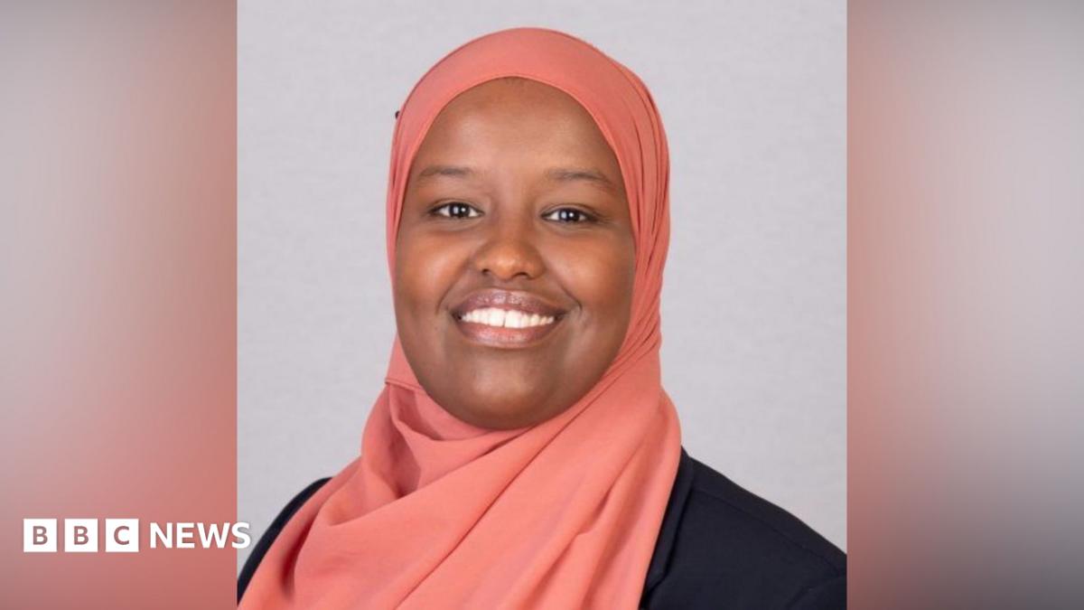 A cut of of Anthony Zurcher wearing a suit and tie in front of a red, black, grey and blue graphic background featuring the US Capitol Building