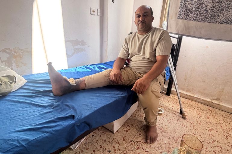 Hakim Mar’i in his family’s apartment with his injured leg, which prevents him from working [Al Jazeera]