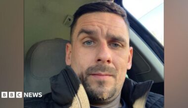 A selfie of Ryan Kettlewell. He is sitting in the front seat of a car. He has short brown hair and dark facial hair.