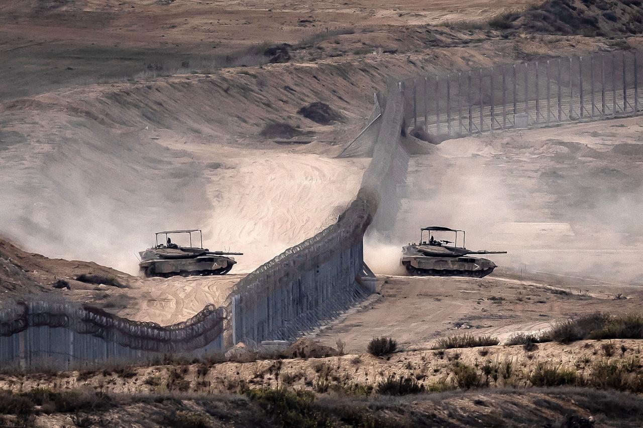 Israeli tanks cross a barbed wire fence at a position along the border with the Gaza Strip and southern Israel on November 12, 2023. (AFP Photo)