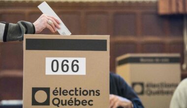 A ballot is dropped into a box with the Élections Québec logo on it.