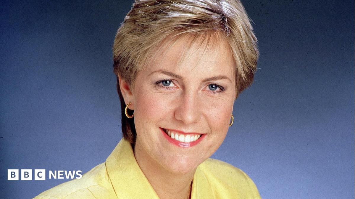 Jill Dando smiles at the camera, wearing a yellow shirt and pink lipstick. She has blue eyes and blonde hair.