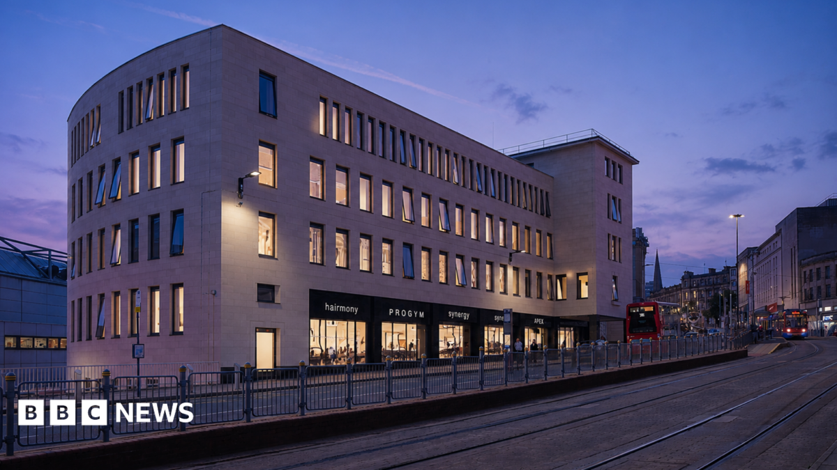 An artist impression of a white brick building lit up at night. It overlooks a city centre main road with shops on the ground floor and dozens of long windows lit up above