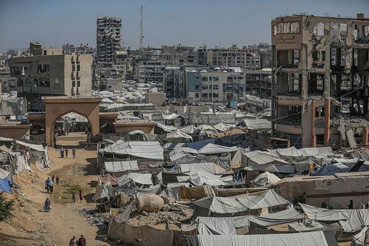 Photograph of cityscape with buildings destroyed by bombs and makeshift tents set up.