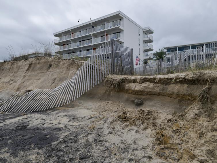 A tall residential building with a partially collapsed and eroded dune.