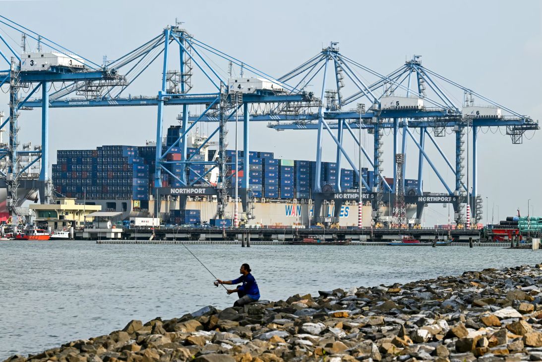 An angler fishes near a cargo ship, docked at Malaysia's North Klang port in Port Klang, on the outskirts of Kuala Lumpur. (Photo by Mohd RASFAN / AFP via Getty Images)