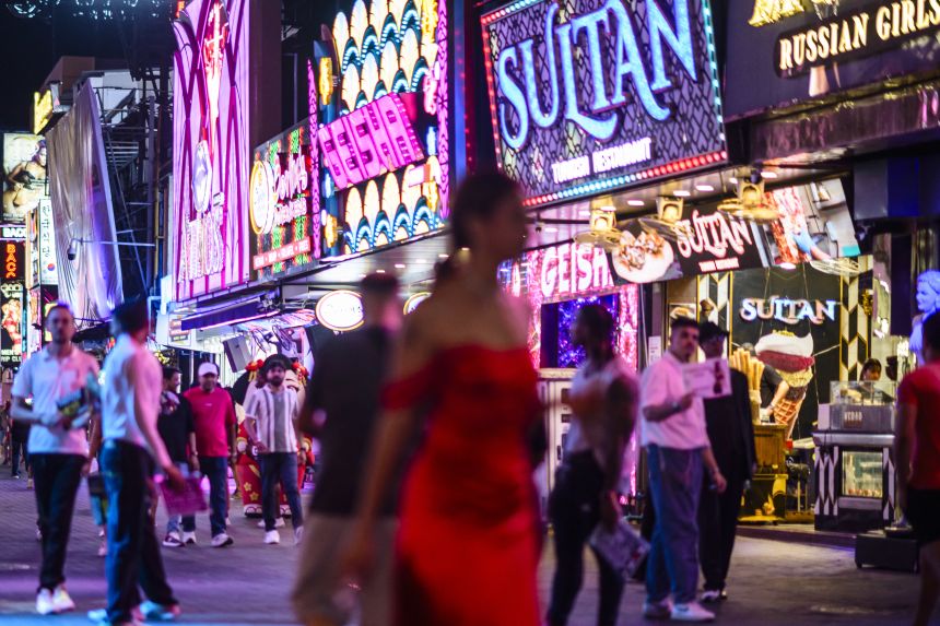 People walk past bars and clubs along Walking Street in Pattaya on July 3, 2026.