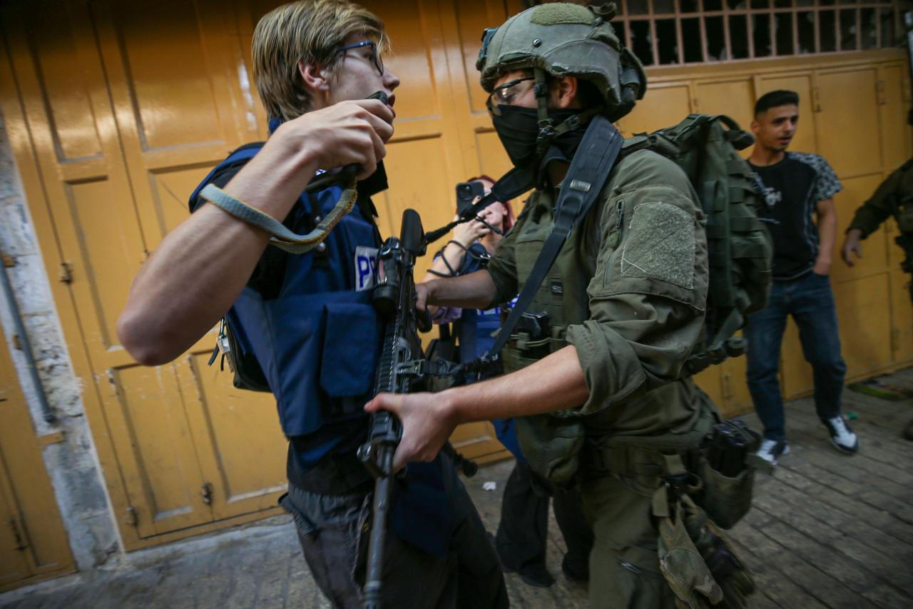 Israeli forces block journalist and activist Andrey X (L) as they set up iron barriers during a raid in the Old City of Hebron, West Bank, Palestine on August 29, 2026. (AA Photo)
