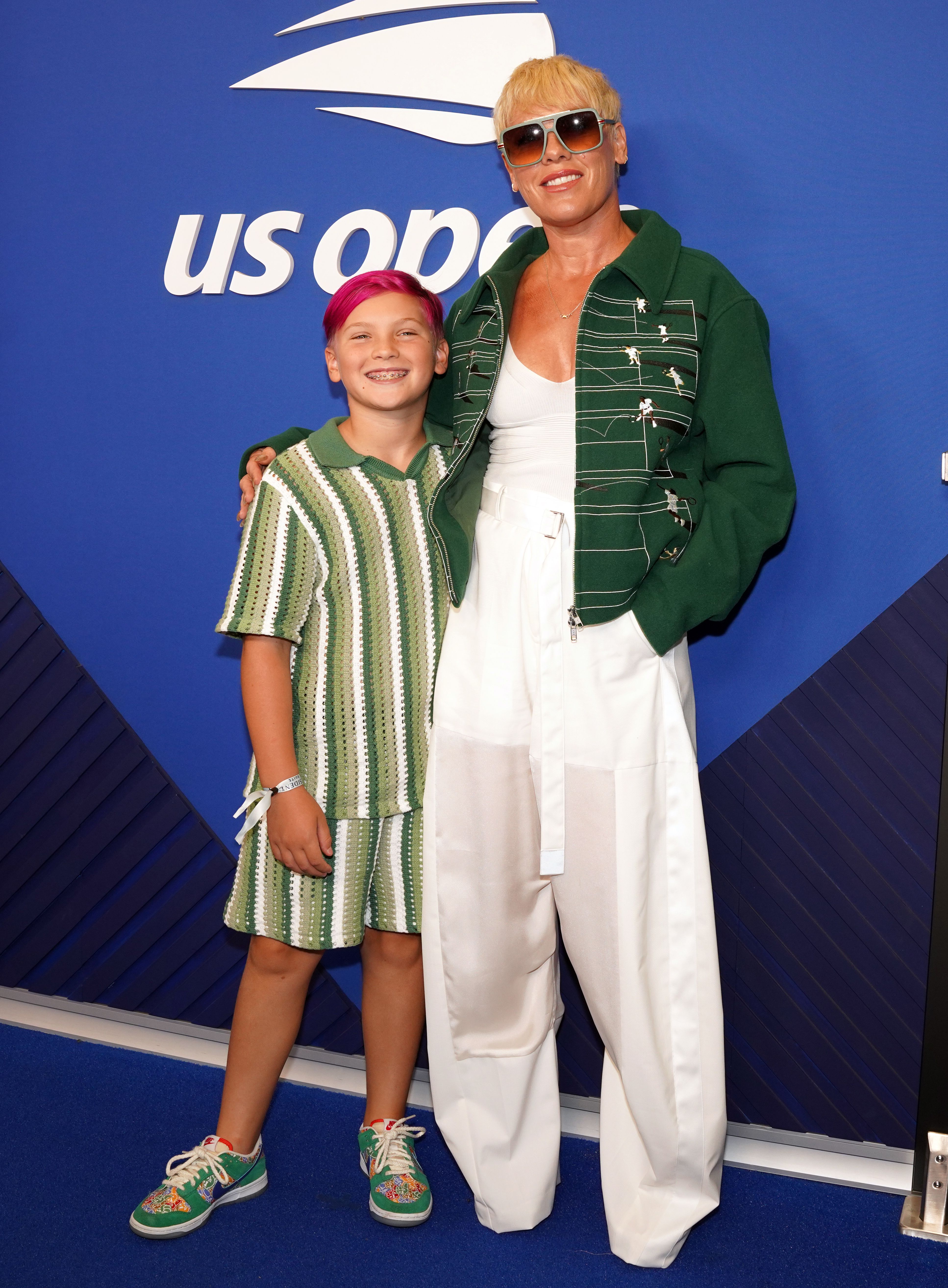 Jameson Moon Hart and Pink posing together on a blue carpet at the US Open.