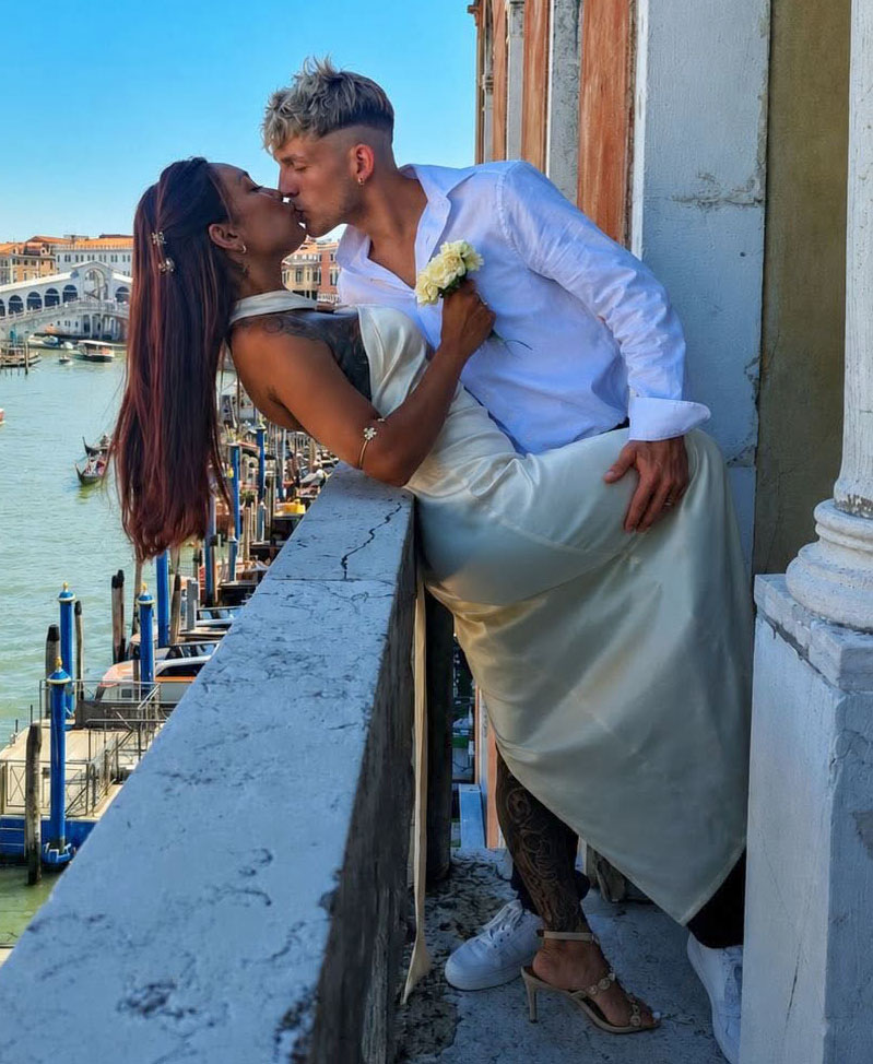 Newlyweds Gabriella Querino and Sean Michieli kissing on a balcony overlooking the Venetian Lagoon.