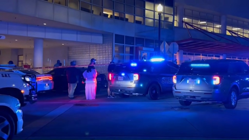 Police vehicles with flashing blue lights and people gathered at Carolyn Crayton Park after a mass shooting.