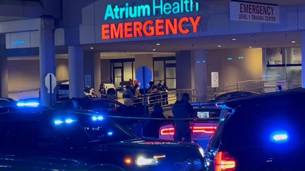 Atrium Health Emergency room entrance at night, with multiple police cars and emergency personnel present.
