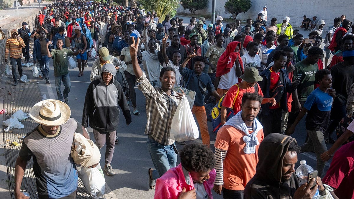 Migrants walk across Trampolin Beach in Ceuta, Spain, as police clear the area.