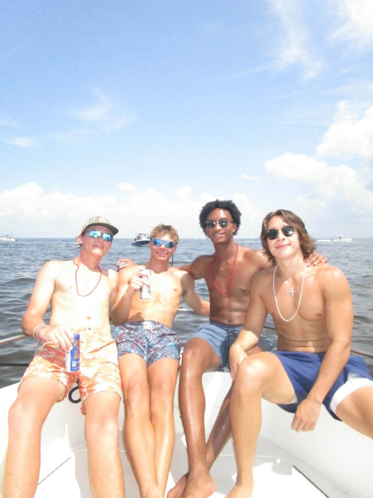 Nolan Wells, second from right, with friends on a boat on the water under a clear sky.