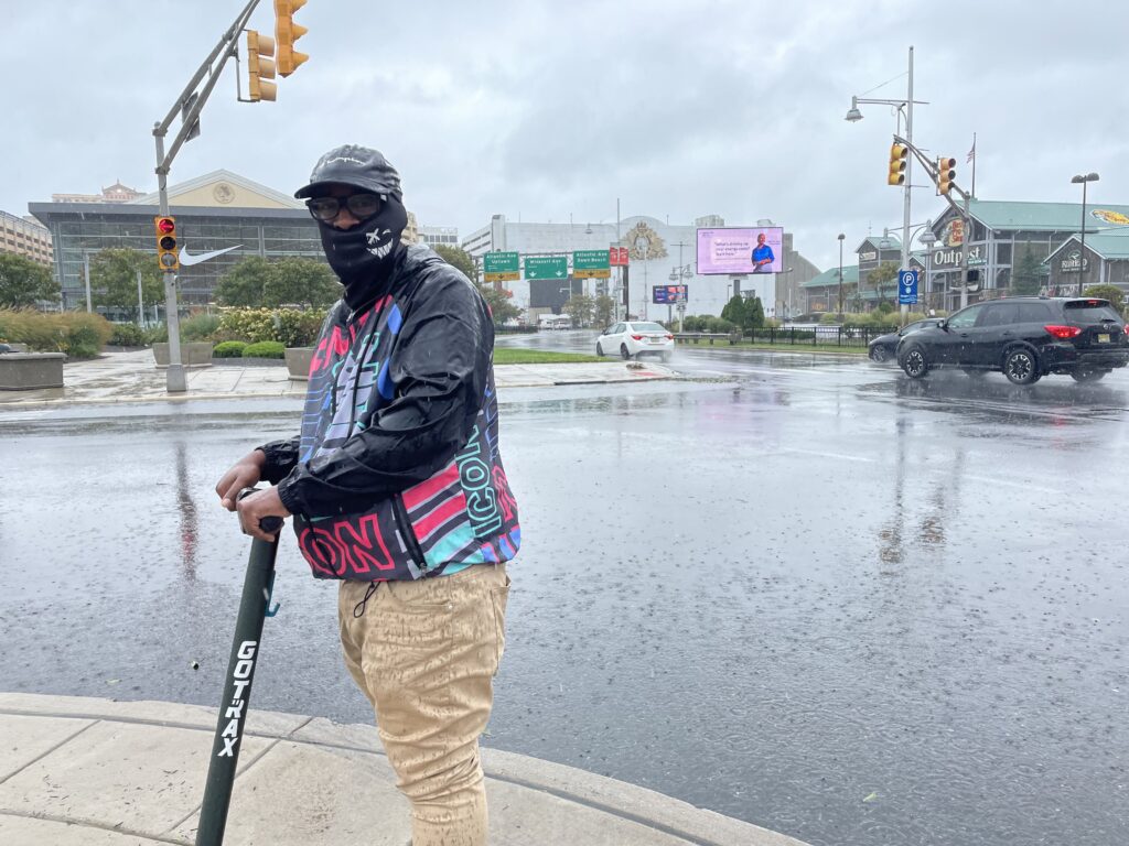 Damere Kellum stands on a scooter while wearing a raincoat in Atlantic City, New Jersey during a nor'easter storm