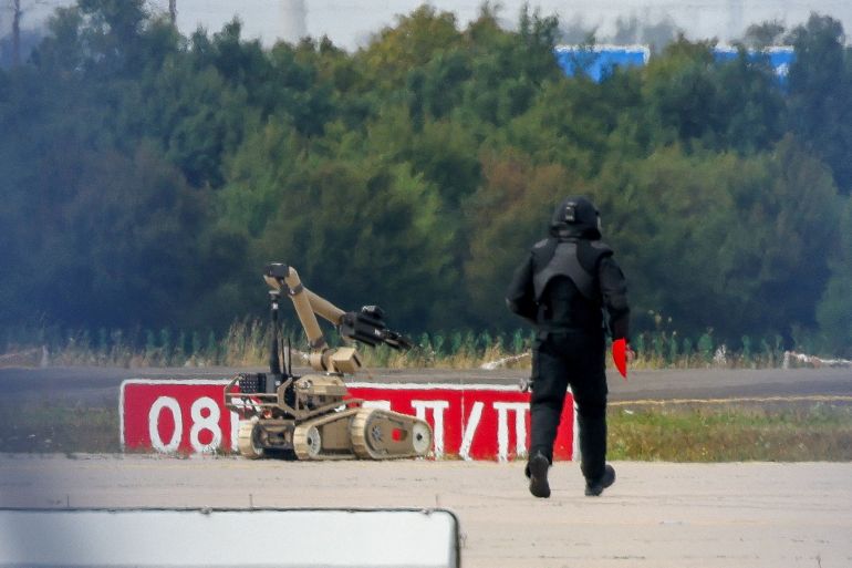 FILE PHOTO: A police officer in protective clothing walks next to an explosive-disarming robot (EOD) at Leipzig/Halle Airport in Schkeuditz, Germany, August 5, 2026, after the police said explosives experts examined a drone found near a runway, and after a DHL cargo aircraft hit an unknown object as it was climbing away from the airport overnight, prompting an unscheduled landing in Hanover, according to a source familiar with the incident. REUTERS/Axel Schmidt/File Photo
