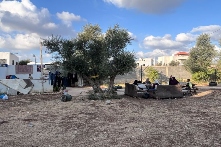 Members of the Zbeidat family sit on couches outside. The room they stay in is on the left [Al Jazeera]