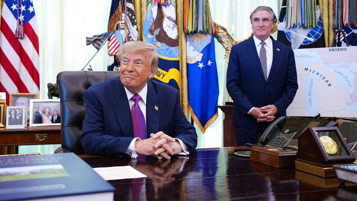 Donald Trump speaks in the Oval Office as Doug Burgum looks on next to a map of Lake America.