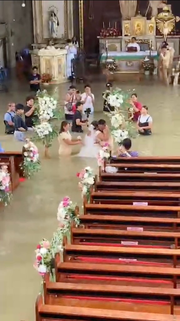 Liean Liza Chico wades through waist-deep floodwater in her wedding dress with Gilbert Chico at the altar of St. John the Baptist Parish.